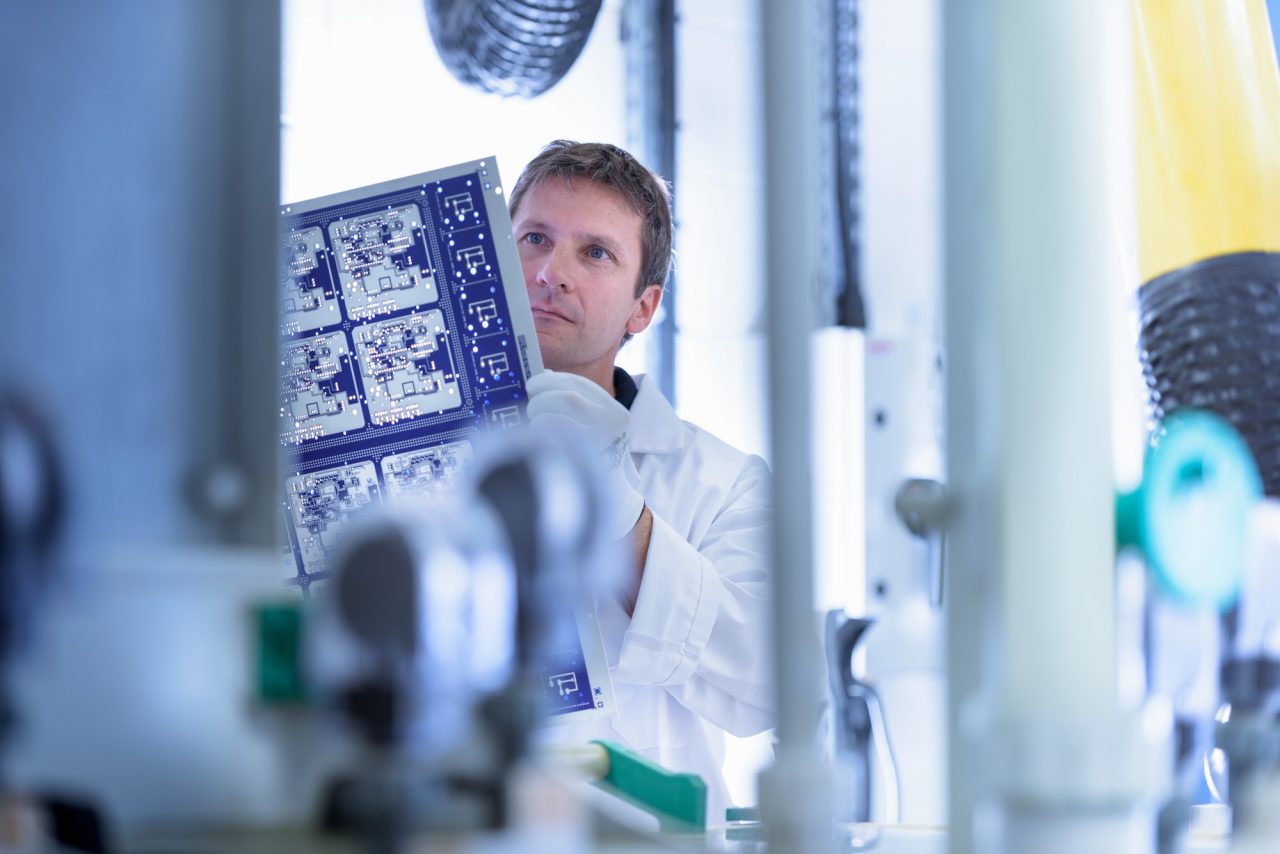 worker inspecting circuit board by processing plant in circuit board factory.jpg